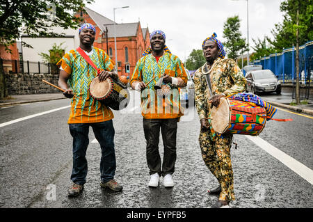 Belfast, Nordirland. 2. August 2015 - drei Männer, gekleidet in traditionellen afrikanischen Kostümen, Schlagzeug spielen während die Feile eine Phobail Parade Credit: Stephen Barnes/Alamy Live News Stockfoto