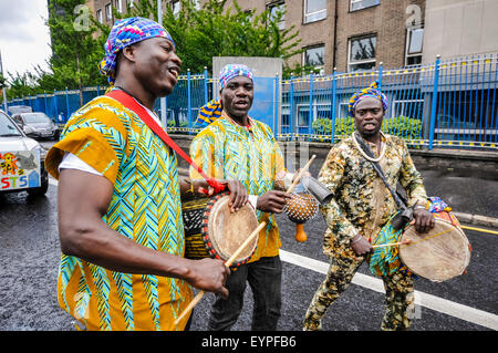 Belfast, Nordirland. 2. August 2015 - drei Männer, gekleidet in traditionellen afrikanischen Kostümen, Schlagzeug spielen während die Feile eine Phobail Parade Credit: Stephen Barnes/Alamy Live News Stockfoto