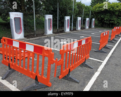 Tesla Ladestationen auf einer Autobahnraststätte in Großbritannien, mit Barrieren um umgesetzt werden Stockfoto