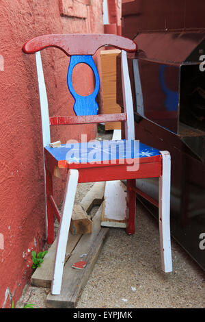 Beschädigt Holz Stuhl neben einem Müllcontainer Stockfoto