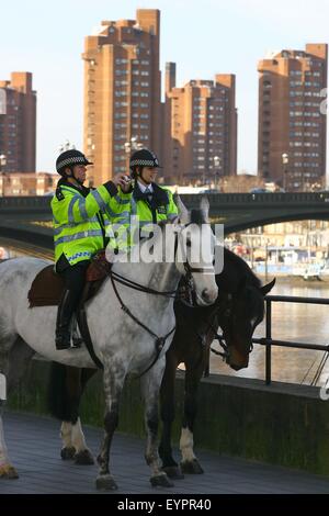 Zwei Polizisten auf dem Rücken der Pferde beobachten, wie Retter einen gestrandeten sieben-Tonnen-nördlichen Bottle-nosed Wal aus der Themse in London überwachen. Stockfoto