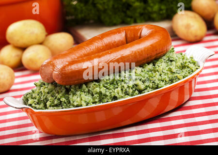 Ein rustikaler Tisch mit ein Gericht mit "trafen sich Boerenkool schlimmsten Fall" oder Grünkohl mit geräucherter Wurst, traditionelle niederländische Gerichte. Stockfoto