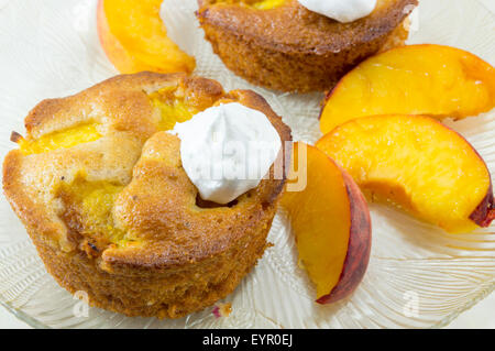 Dekoriert mit Sahne und frischen Pfirsich Scheiben auf dem Silbertablett serviert hausgemachte Obst-muffins Stockfoto