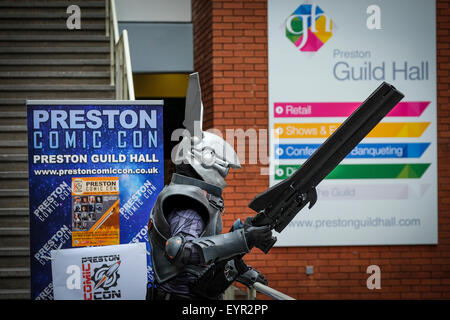 Preston, UK. Comic-Con-Event in Preston Guild Hall mit Mann in futuristischen Kostüm und großen Gewehr neben Event Banner. Stockfoto