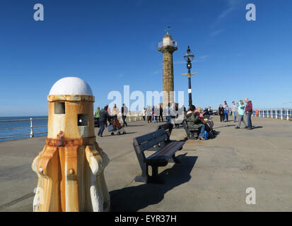 Touristen genießen die Frühlingssonne auf die beliebte Whitby West Pier. Stockfoto