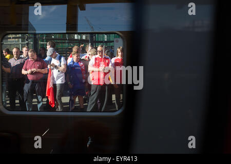Fußball-Fans auf eine Zug-Plattform wartet, gesehen durch ein Zugfenster Stockfoto