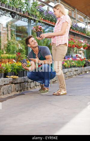 Lächelnde junge Frau kaufen Blumen in einem Topf in einem Garten-center Stockfoto