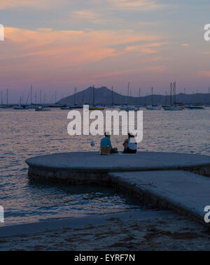 Romantisch zu zweit am Meer sitzen auf einem Anlegehafen mit einem romantischen Picknick in Puerto Pollensa Stockfoto