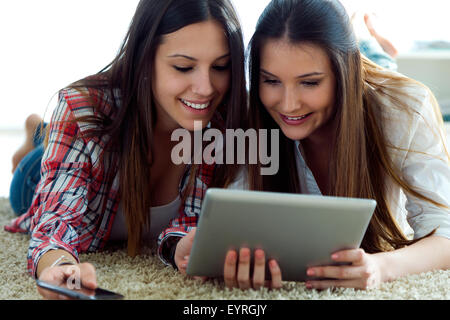 Porträt von zwei schöne junge Frau Freunde mit digital-Tablette zu Hause. Stockfoto