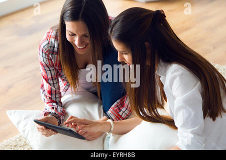 Porträt von zwei schöne junge Frau Freunde mit digital-Tablette zu Hause. Stockfoto