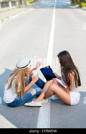 Glückliche junge Frauen mit Vintage Musik Kopfhörer und eine Tasse Kaffee zum mitnehmen, Internetsurfen auf TabletPC zusammen und Spaß Stockfoto