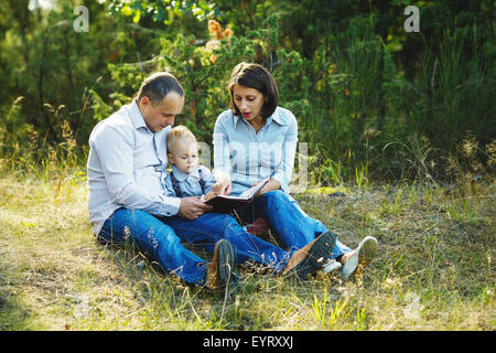 Familie Lesebuch im park Stockfoto