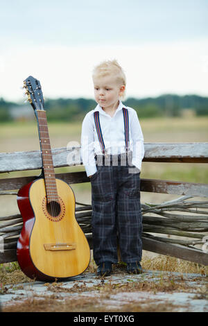 kleiner Junge mit Gitarre vor Ort Stockfoto