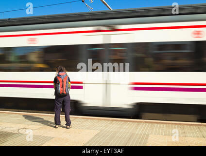 Junge Frau mit Rucksack unterwegs Plattform als RENFE Zuggeschwindigkeit Vergangenheit in Spanien ansehen Stockfoto