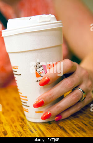 Zarte Frauenhand mit bunt bemalte Fingernägel, hält eine Tasse Kaffee Dunkin ' Donuts Stockfoto