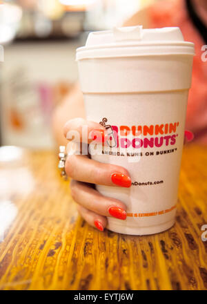 Zarte Frauenhand mit bunt bemalte Fingernägel, hält eine Tasse Kaffee Dunkin ' Donuts Stockfoto