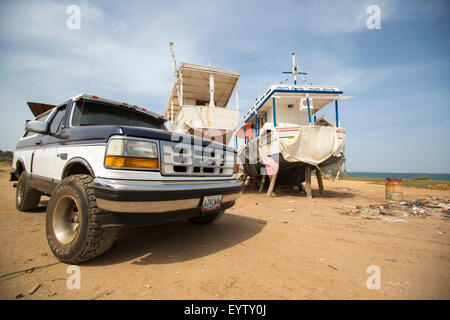 4 x 4 Ford in einer Werft in der Nähe von zwei Fischerboote am Strand mit dem Meer im Hintergrund stehend geparkt. Insel Margarita. Stockfoto