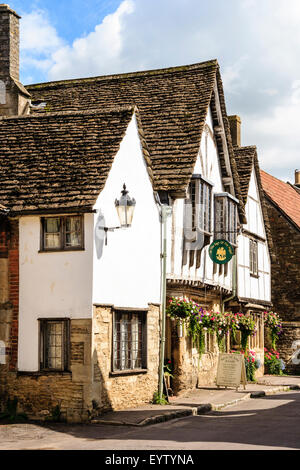 England, Lacock. Blick entlang des 16. Jahrhunderts malerische Kirche Straße, die zwei Geschichte Zeichen des Angel Inn, ein Holz und weißem Putz Taverne. Stockfoto