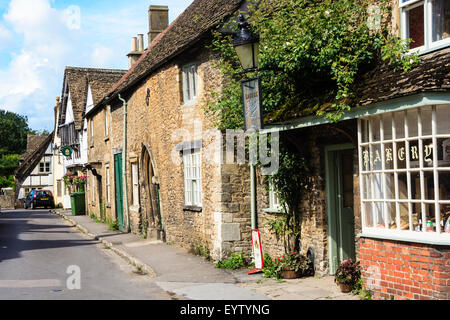 England, Lacock, Cotswolds. Blick entlang der Church Street, 15. Jahrhundert - 18. Jahrhundert Cotswold Häuser aus Stein und Dorfbäckerei. Malerische Ansicht. Stockfoto