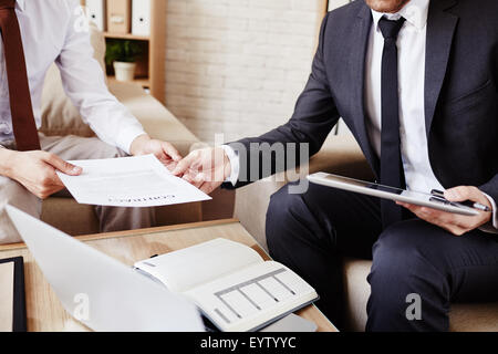 Unternehmer geben Dokument an seine Kollegen bei der Sitzung Stockfoto