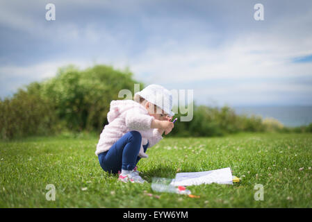 kleines Mädchen sitzen auf dem Rasen Stockfoto