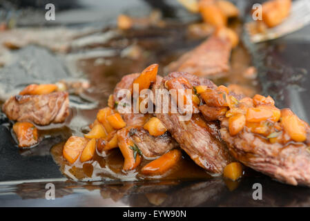 sehr lecker, frisch zubereitet Gericht aus Schweinefleisch mit Sauce auf der schwarzen Platte Stockfoto