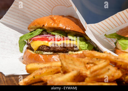 frische Burger und Pommes Frites auf einem Holztablett Stockfoto