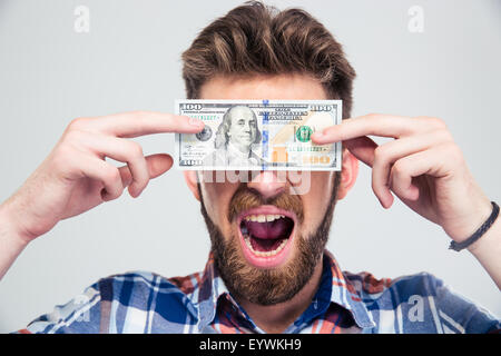 Porträt eines Mannes für seine Augen mit der USA-Dollar Bill und schreien auf einen weißen Hintergrund isoliert Stockfoto