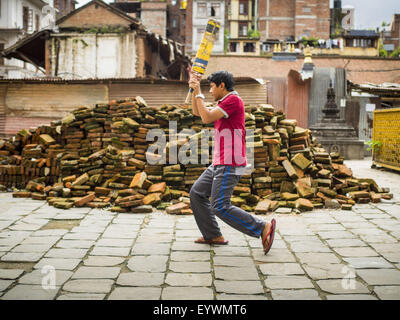 Kathmandu, Nepal. 1. August 2015. Jungen Praxis Cricket mit der Wimper vor einem Haufen von Steinen erholt für Erdbeben. Das Erdbeben in Nepal am 25. April 2015, (auch bekannt als der Gorkha Erdbeben) mehr als 9.000 Menschen getötet und verletzt mehr als 23.000. Es hatte eine Stärke von 7,8. Das Epizentrum lag östlich der Stadtteil Lamjung, und seine Hypozentrum lag in einer Tiefe von ca. 15Â Kilometer (9.3Â Meile). Es war die schlimmste Naturkatastrophe seit 1934 Nepal Nepal Streikrecht '' "Bihar Erdbeben. Das Erdbeben löste eine Lawine auf dem Mount Everest, töten mindestens 19. Die earthquak Stockfoto