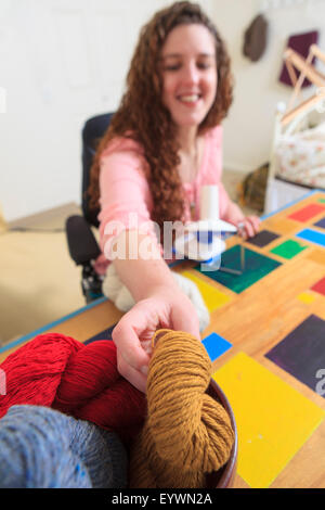 Frau mit Muskeldystrophie, die Arbeit mit ihr stricken Stockfoto