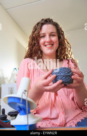 Frau mit Muskeldystrophie, die Arbeit mit ihrem Garn-Wickler für ihr Hauptgeschäft Stockfoto