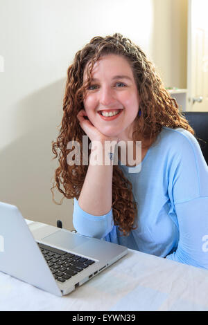 Frau mit Muskeldystrophie, die Arbeiten an ihrem Laptop in ihrem Büro Stockfoto