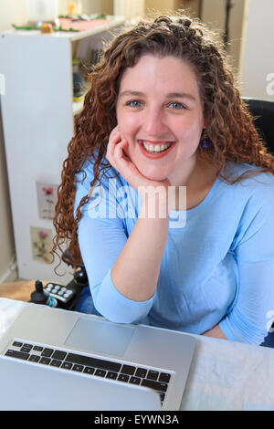 Frau mit Muskeldystrophie, die Arbeiten an ihrem Laptop in ihrem Büro Stockfoto