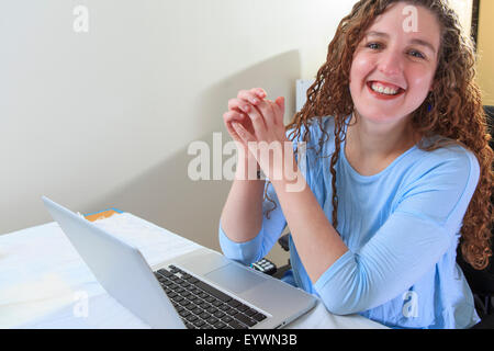 Frau mit Muskeldystrophie, die Arbeiten an ihrem Laptop in ihrem Büro Stockfoto