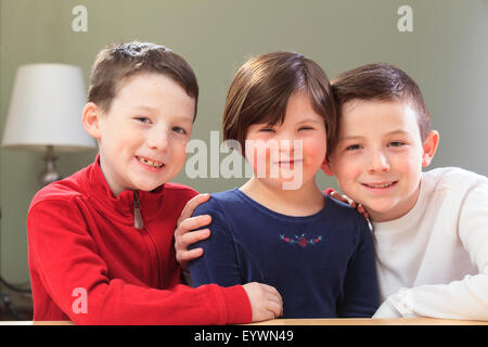Kleines Mädchen mit Down-Syndrom, spielen mit ihren Brüdern Stockfoto