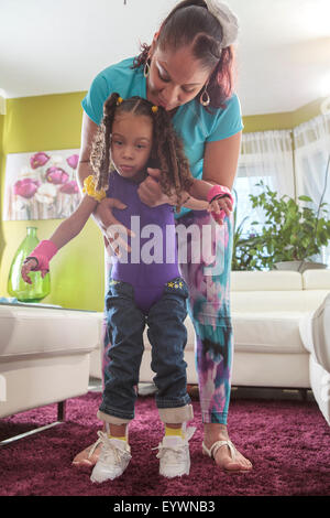 Mutter hilft kleinen Tochter mit zerebraler Lähmung zu Fuß Stockfoto