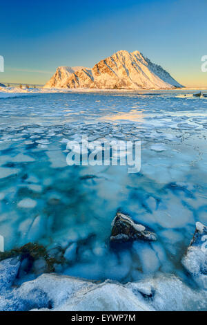 Berge von Gymsoya (Gimsoya) aus Smorten spiegelt sich im kristallklaren Meer noch teilweise gefroren, Lofoten-Inseln, Arktis, Norwegen Stockfoto