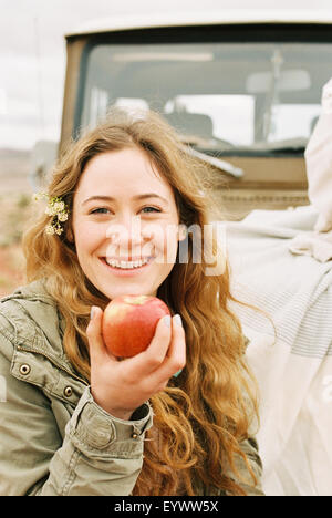 Eine junge Frau hält einen enthäuteten roten Apfel. Stockfoto