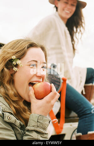 Zwei junge Frauen, eine in einen Apfel beißen. Stockfoto