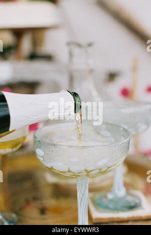 Champagner aus der Flasche in ein Glas gegossen wird. Stockfoto