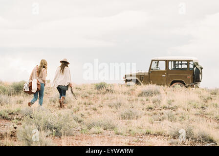 Zwei Frauen, die zu Fuß in Richtung 4 x 4 in eine Wüste geparkt. Stockfoto