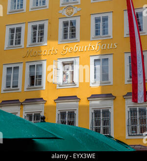 Salzburg, Salzburger Land, Österreich.  Mozarts Geburtshaus, mit einem Porträt des Komponisten durch ein Fenster sichtbar. Stockfoto