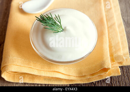 Saure Sahne (weisse Sauce) mit Dill auf Holztisch, horizontale hautnah Stockfoto