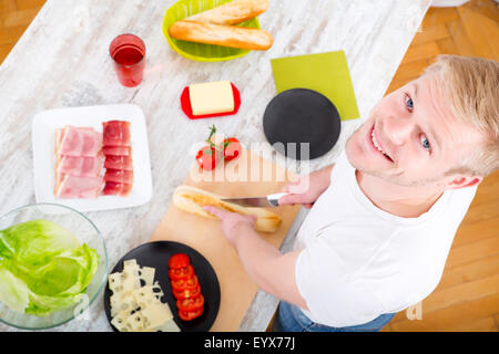 Ein junger Mann einen Sandwich in der Küche vorbereiten. Stockfoto