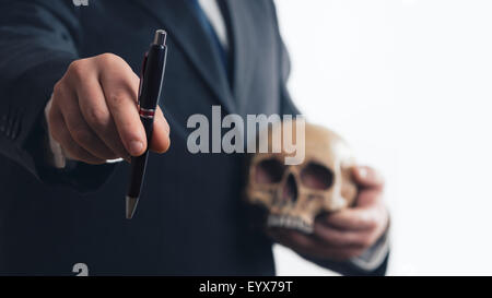 Geschäftsmann bietet einen Stift, einen Schädel in der hand Stockfoto