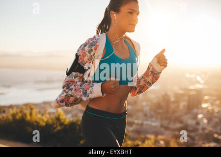 Schuss von überzeugt junge Läufer in der Sportswear auf Morgenlauf. Frau mit hellem Sonnenlicht morgens joggen. Stockfoto