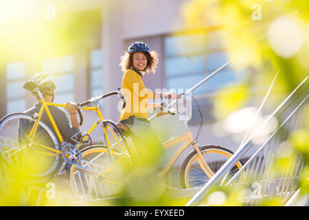 Lächelnde Frau mit Fahrrad in der Stadt Stockfoto