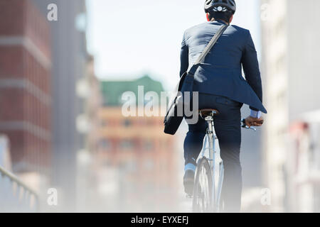 Geschäftsmann in Anzug und Helm Reiten Fahrrad in Stadt Stockfoto