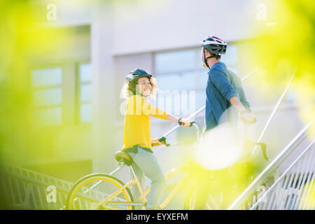 Mann und Frau mit Helmen auf Fahrrädern sprechen Stockfoto