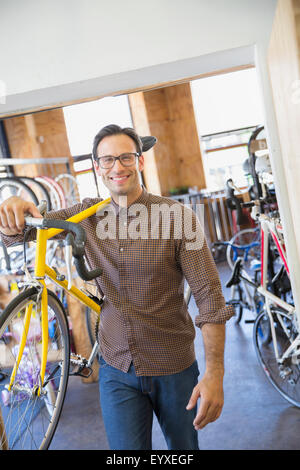 Porträt, Lächeln Mann mit Brille tragen Fahrrad im Fahrradshop Stockfoto